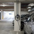 Electric vehicle plugged into a wall-mounted charger on a pillar inside a covered apartment basement car park