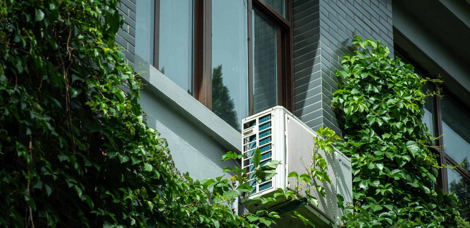 External mounted heat pump unit fitted below a window on a sunlit Auckland house