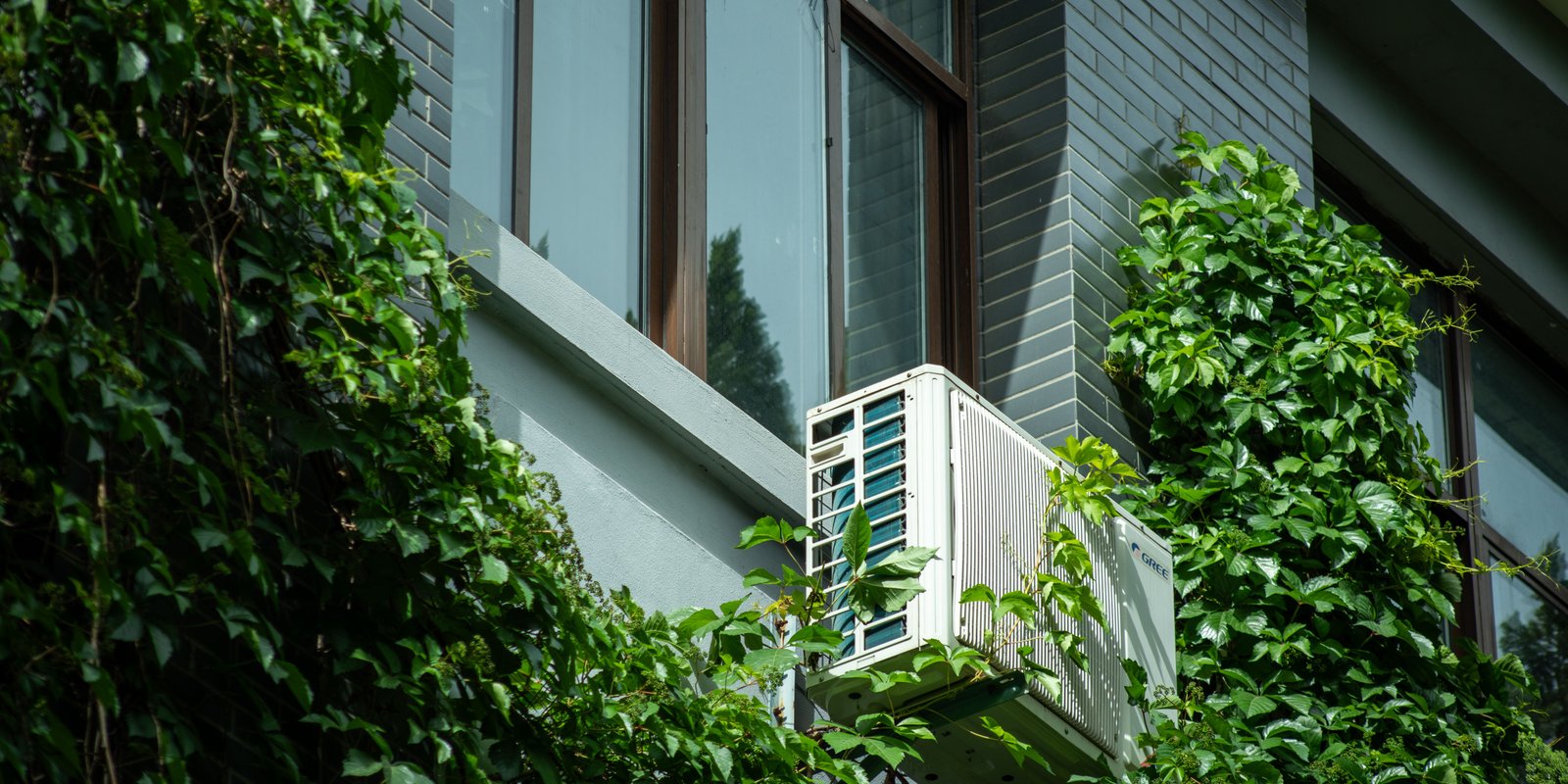 External mounted heat pump unit fitted below a window on a sunlit Auckland house