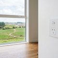 White double power point on a wall in an empty new home, beside a window overlooking rolling green farmland