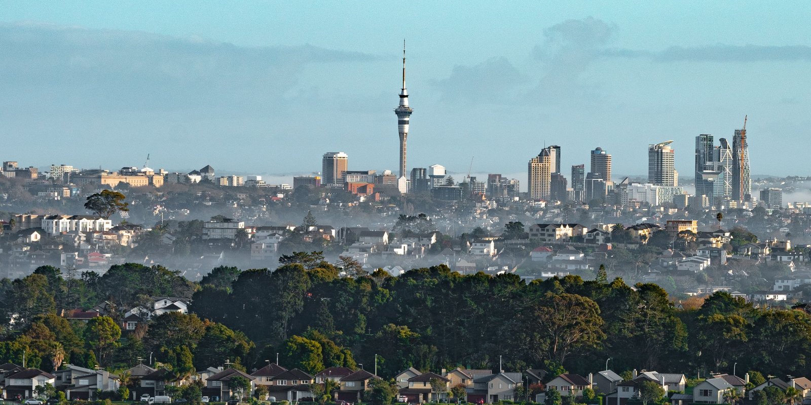 Scenic view of Auckland's skyline and suburban homes at dawn, showcasing the urban landscape and Sky Tower