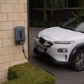 A white electric car charging on a wall-mounted EV charger in Pukekohe, New Zealand, showcasing modern eco-friendly transportation