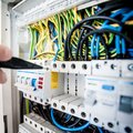 Hand of electrician working on a circuit breaker panel with colorful wires, ensuring safe electrical connections